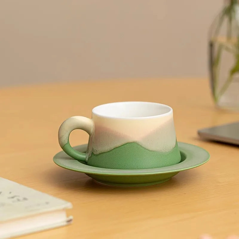 Zielona filiżanka Sento ze spodkiem na biurku obok laptopa