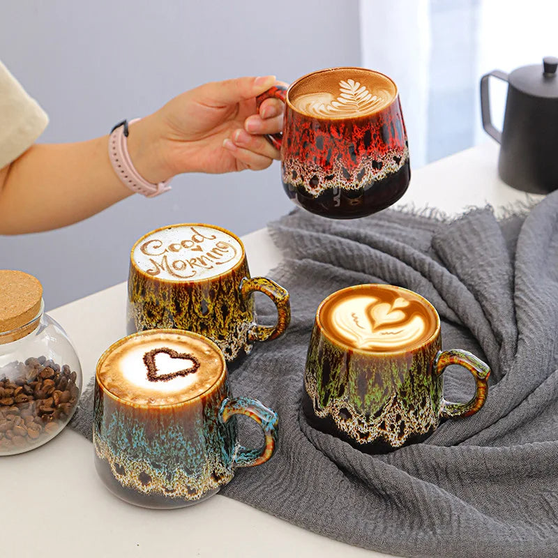 Kolorowe kubki Aurora z kawą i latte art, jeden czerwony kubek trzymany w dłoni