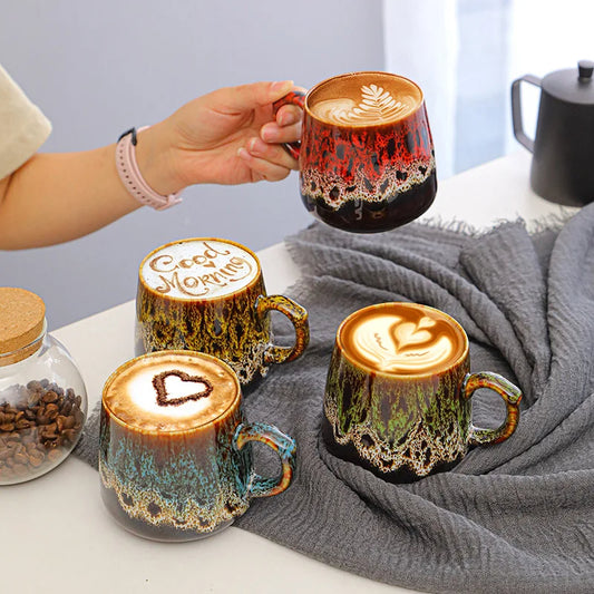 Kolorowe kubki Aurora z kawą i latte art, jeden czerwony kubek trzymany w dłoni