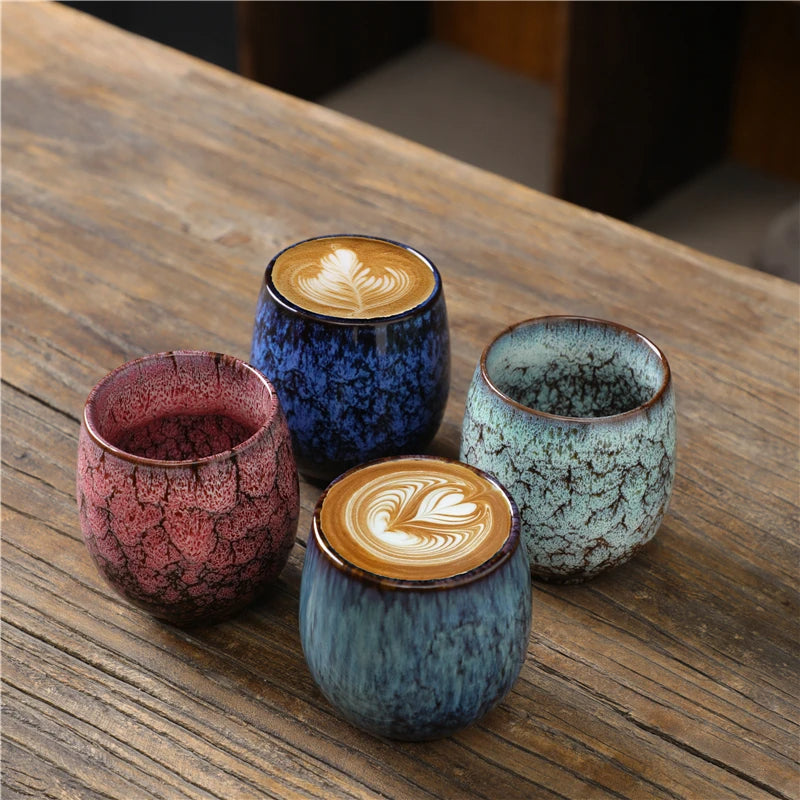Kubki Yoru w różnych kolorach na drewnianym blacie, dwa napełnione kawą z latte art