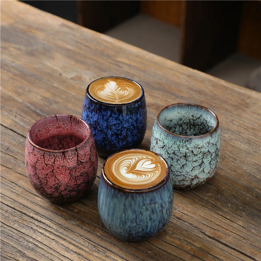 Kubki Yoru w różnych kolorach na drewnianym blacie, dwa napełnione kawą z latte art